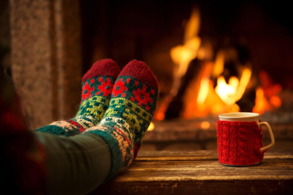 Feet with woolly socks keeping warm by the fire.